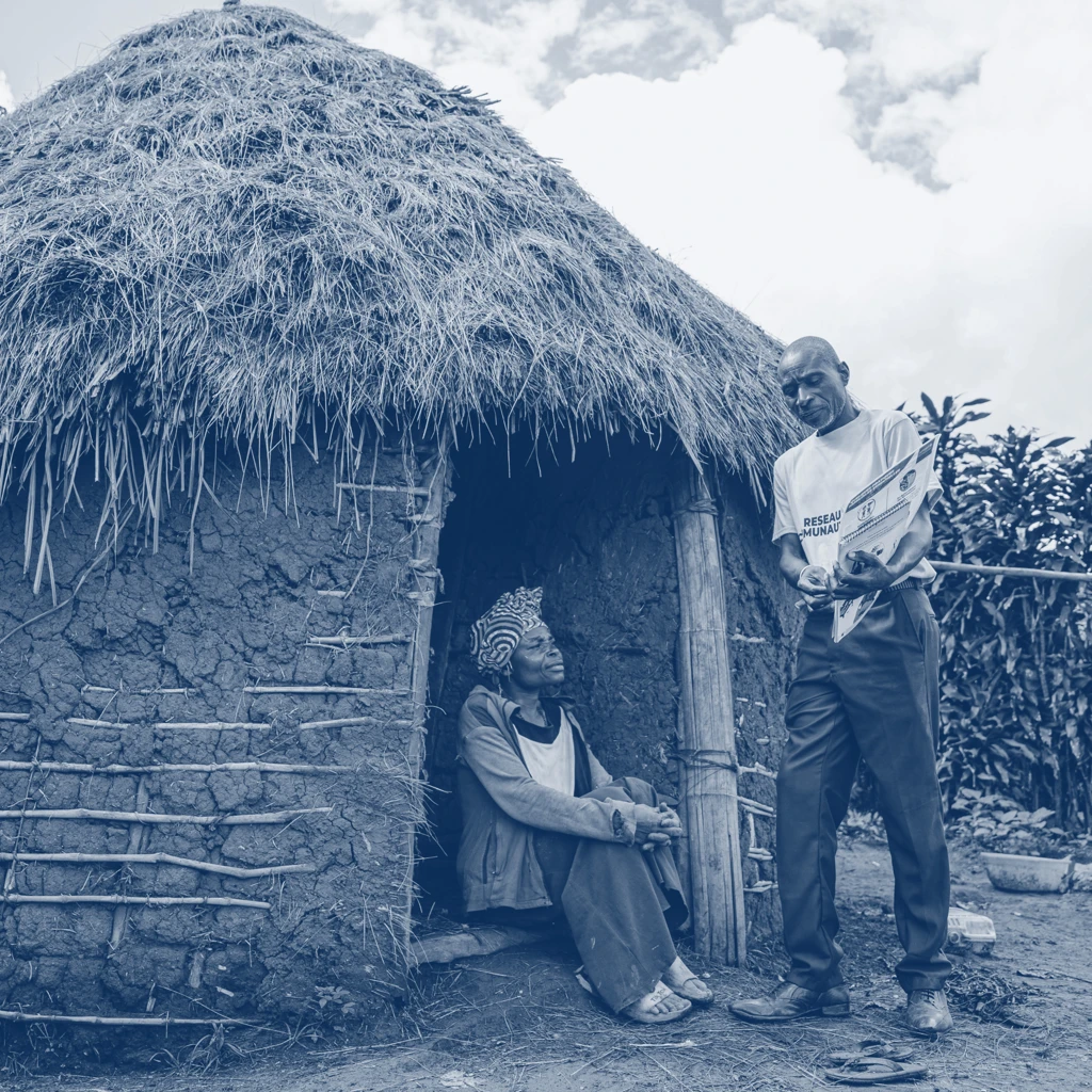 people talking outside settlement with thatched roof